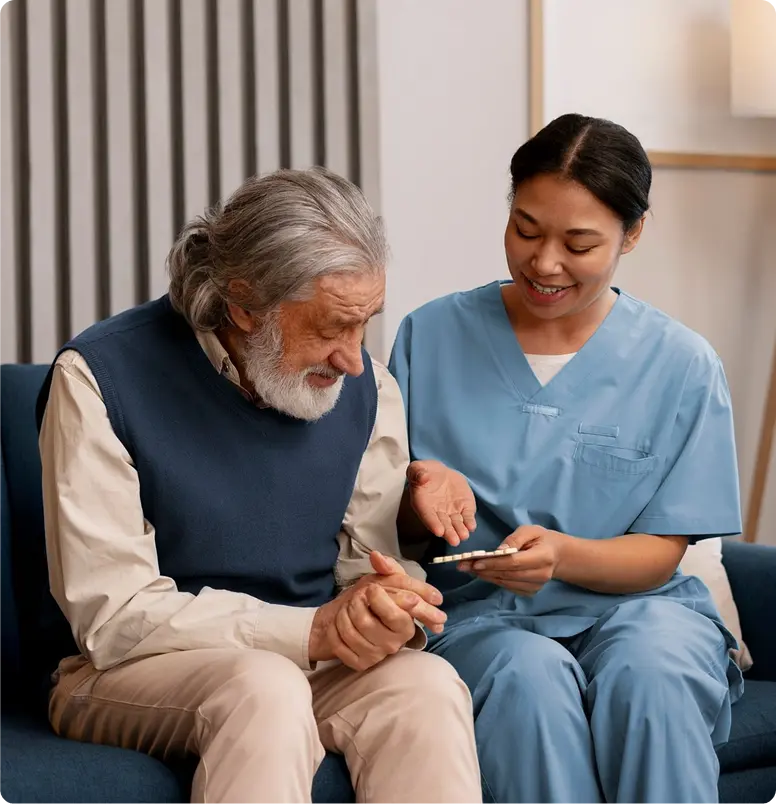 A nurse and an elderly man sit together on a couch