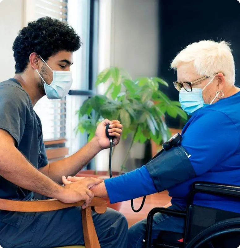 A nurse measures the blood pressure of an elderly woman in a clinical setting, ensuring her health and well-being.