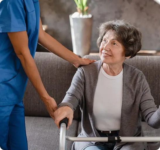 A nurse assists an elderly woman using a walker
