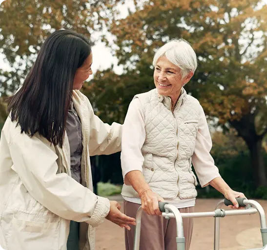 A woman assists an older woman using a walker